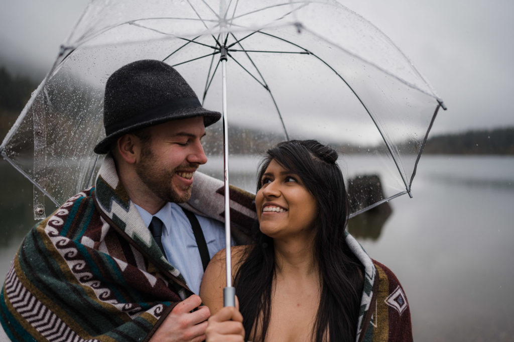 A couple standing under a clear umbrella during their rainy elopement in Washington state.