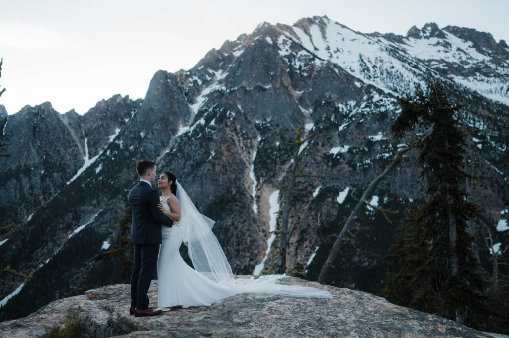 A couple standing in front of a mountain peak during their North Cascades National Park elopement.
