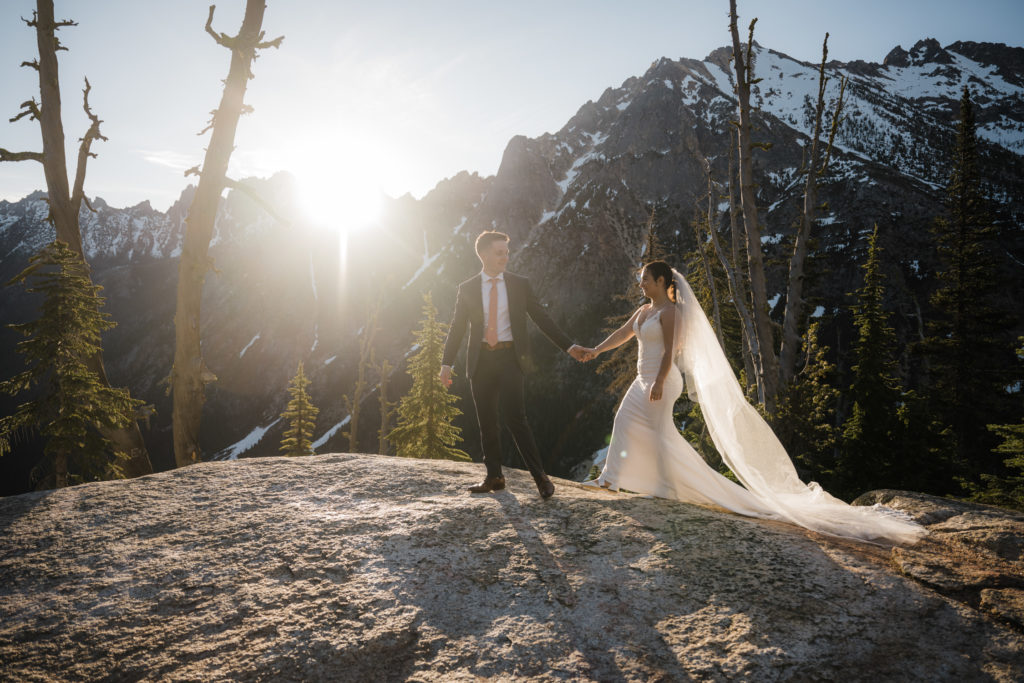 A couple walking hand in hand as the sun sets behind them during their North Cascades National Park elopement.