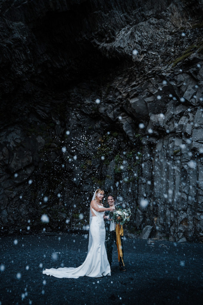 Eloping couple popping champagne on a black sand beach near Vik, Iceland