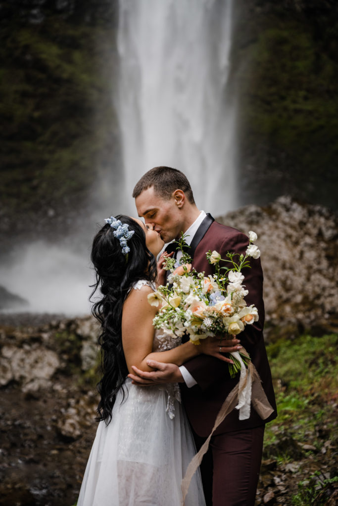 A couple kissing in front of a waterfall at one of the best places to elope in oregon!