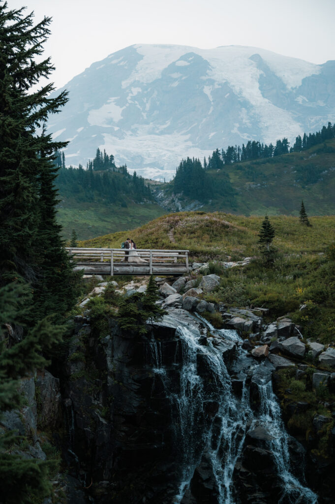 eloping couple standing on the bridge at Myrtle Falls in Mount Rainier National Park 