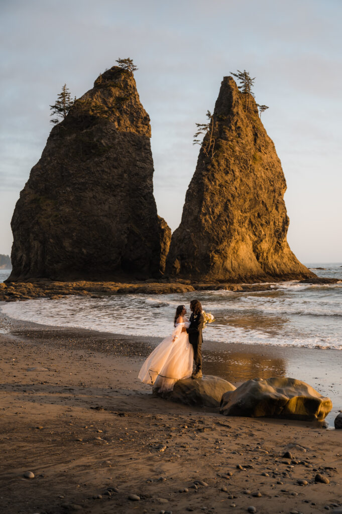 eloping couple standing in front of the sea stacks at Rialto Beach in Olympic National Park