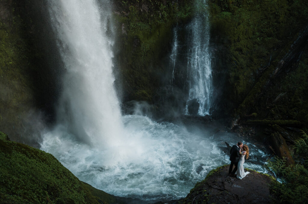 couple posing next to a waterfall in the pacific northwest 