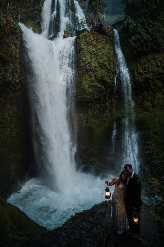 Couples hiking elopement to Falls Creek Falls in Washington State with moody lantern photos