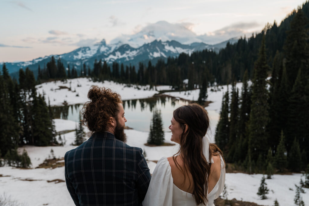 couple watching the sunset during their elopement at tipsoo lake in mount rainier national park 