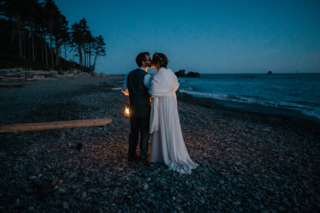 Couple walking down Ruby Beach with lanterns after eloping in Olympic National Park, Washington State