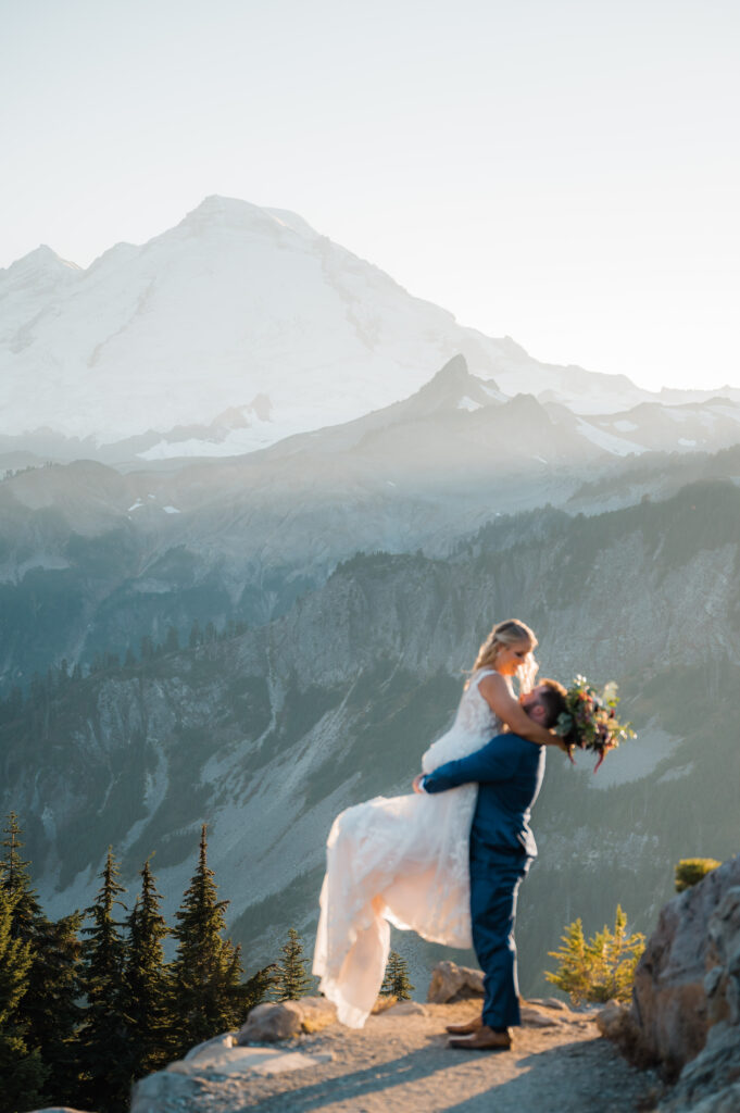 Bride being lifted up by the groom with Mt. Baker in the background