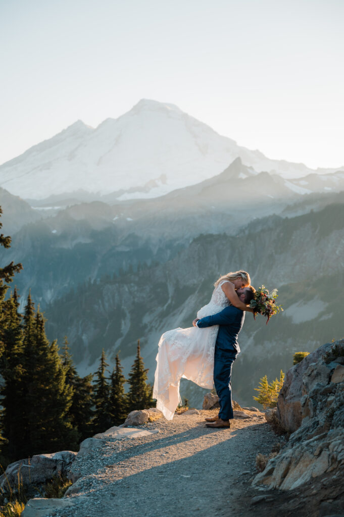 Bride being lifted up for a kiss with views of Mount Baker in the background