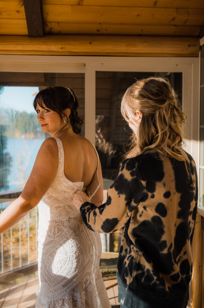 daughter helping her mother zip up her wedding dress