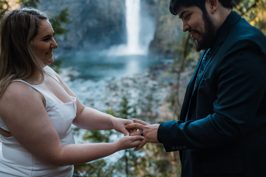 Bride and groom exchanging rings in front of Snoqualmie Falls in Washington State