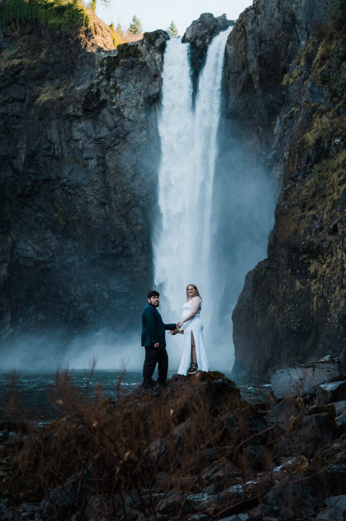 Bride and groom standing in front of Snoqualmie Falls after eloping in Washington