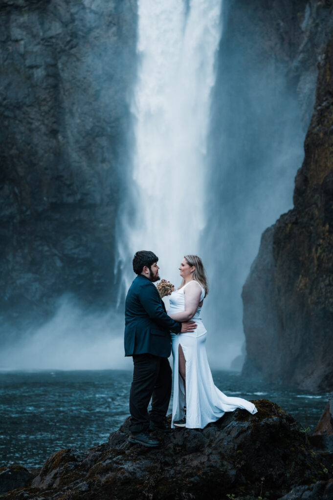 Bride and groom standing in front of Snoqualmie Falls after getting married in Washington State