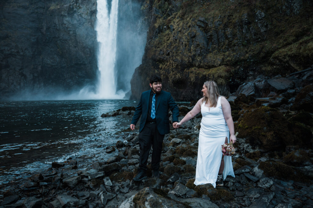 Couple holding hands and walking in front of Snoqualmie Falls