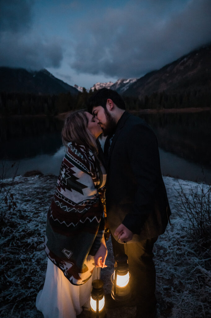 Bride and groom kissing while holding lanterns during their elopement day at Gold Creek Pond in Washington State