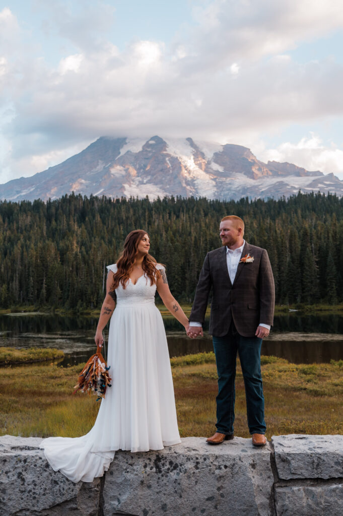 Bride and groom holding hands in front of Mount Rainier during their elopement day at Reflection Lake 