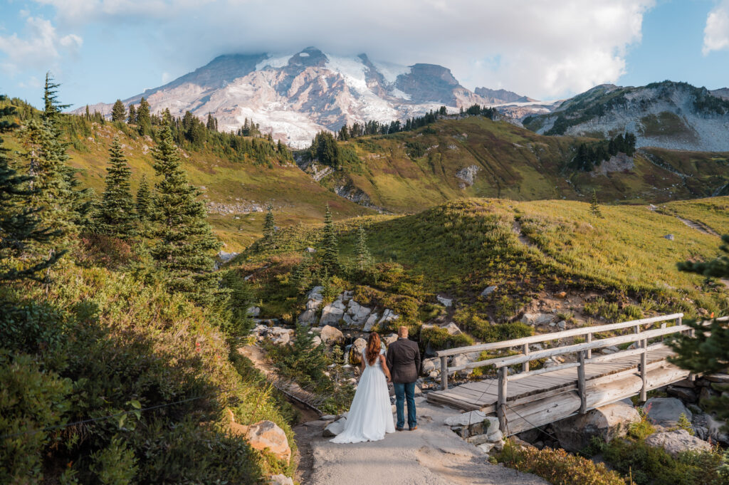 Couple standing in front of Myrtle Falls on their elopement day with Mount Rainier in the background