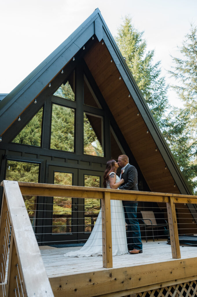 Couple posing in front of their A-Frame cabin they rented in Packwood during their elopement day at Mount Rainier National Park 