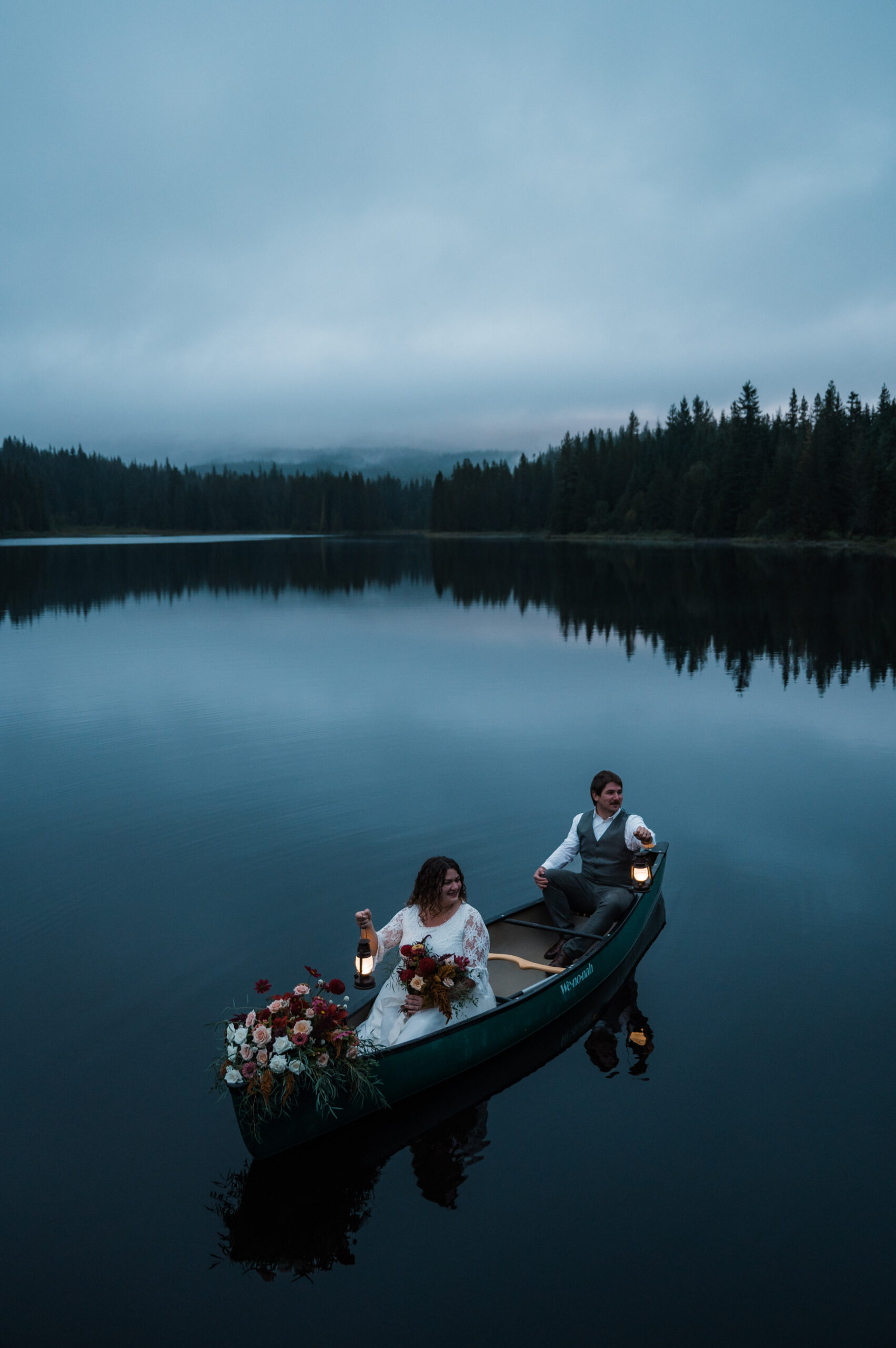 Couple holding lanterns during their canoe elopement at Trillium Lake near Mount Hood Oregon