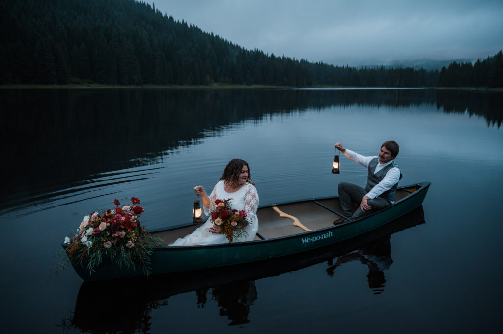 bride and groom holding lanterns in a canoe on their wedding day at Trillium Lake near Mount Hood Oregon