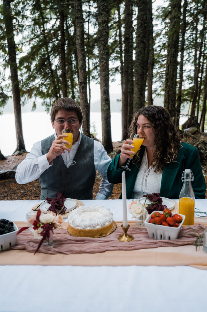 bride and groom drinking mimosas during their brunch picnic on their elopement day at Trillium Lake