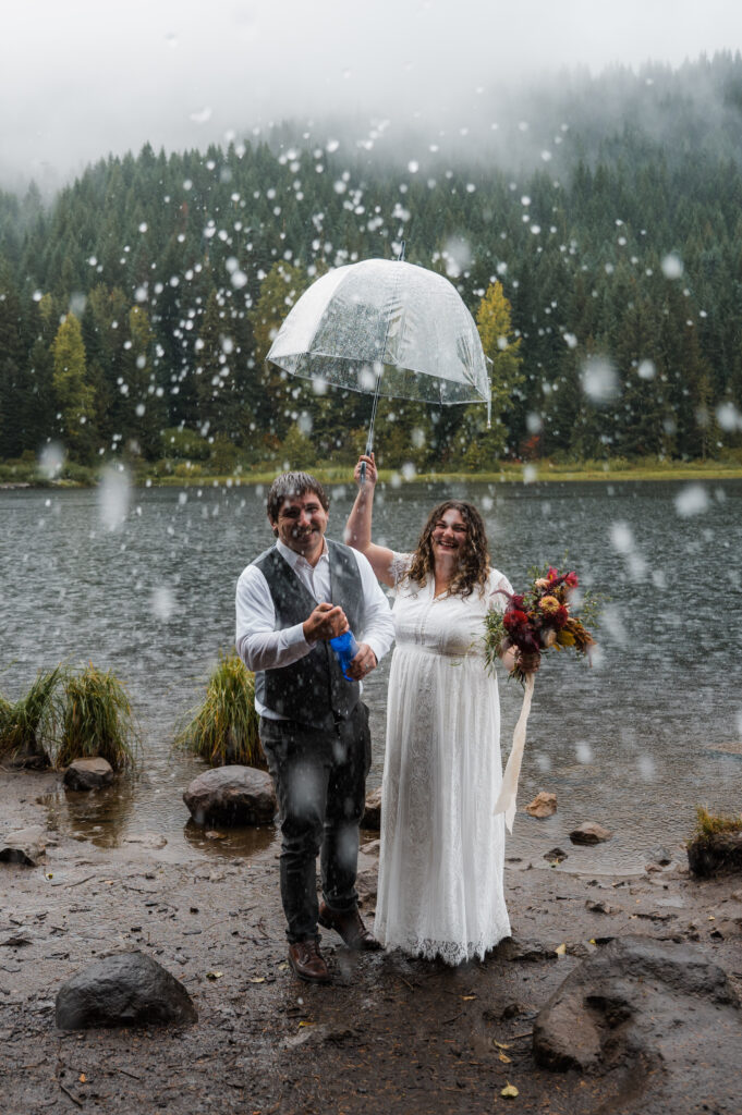 bride and groom popping champagne during their elopement day at Trillium Lake near Mount Hood, Oregon