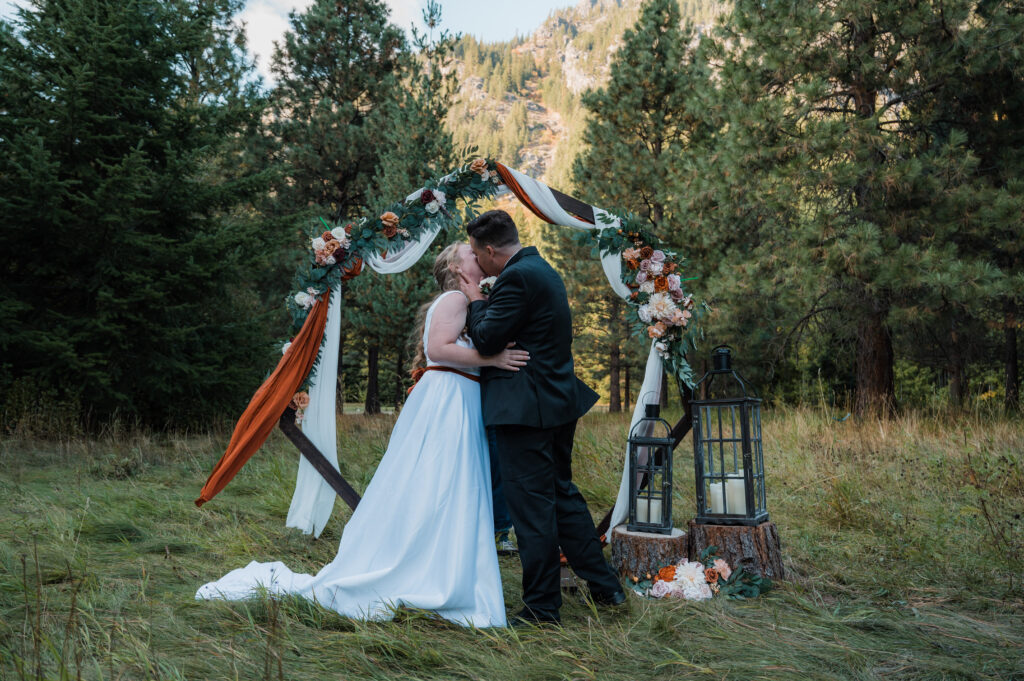 Bride and groom sharing their first kiss during their ceremony at a cabin outside Leavenworth, Washington