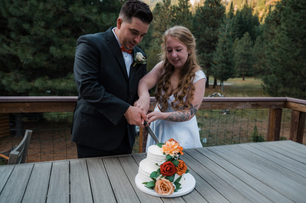 Bride and groom cutting cake with autumn colored flowers