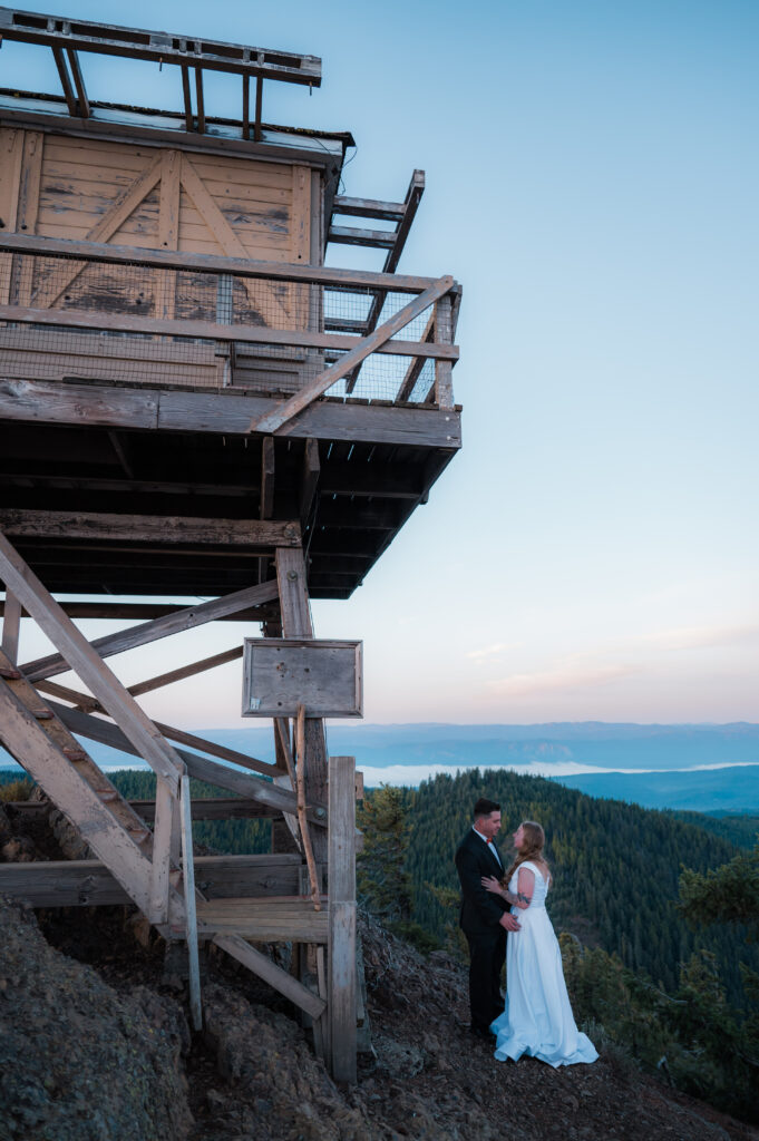 Eloping couple standing in front of Red Top Fire Lookout in Washington State
