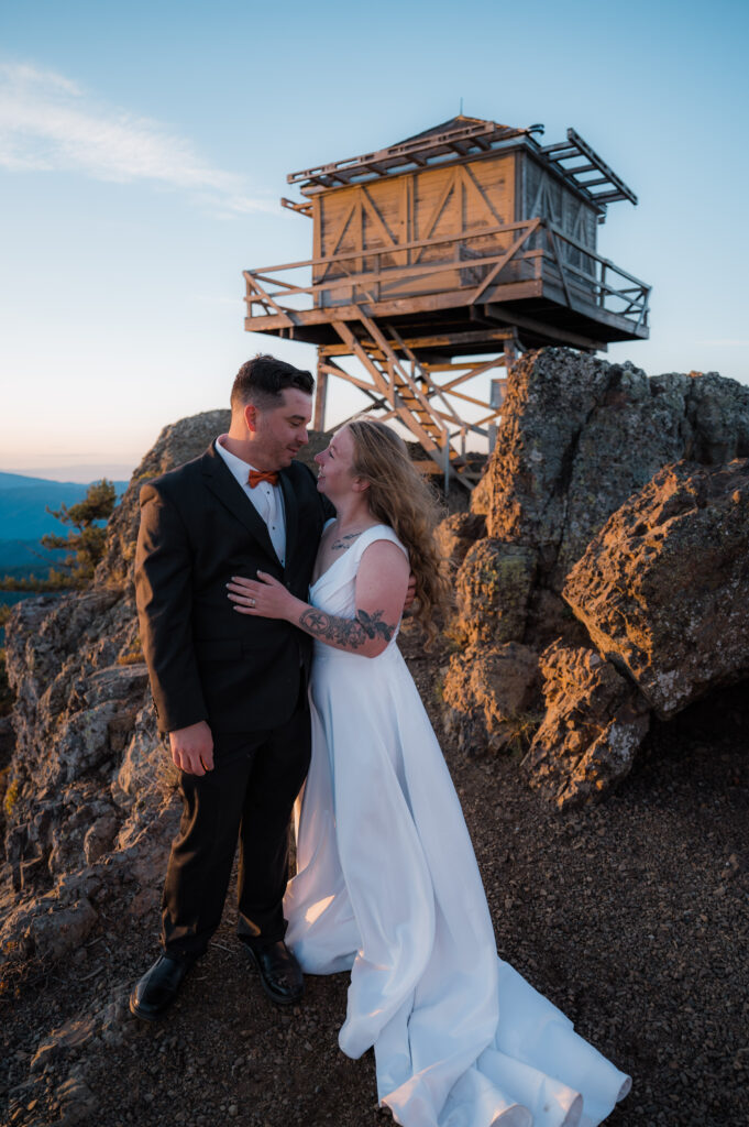 Eloping couple standing in front of a fire lookout in Washington State