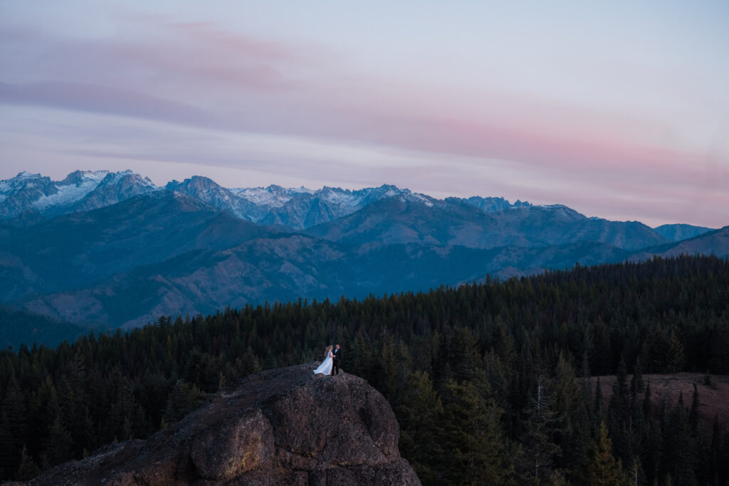 Bride and groom watching the sunrise over the mountains at Red Top Fire Lookout in Washington State