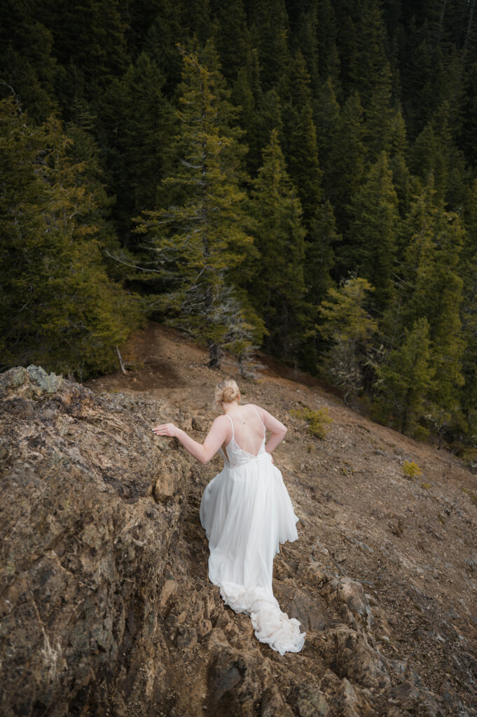 bride climbing down a mountain in her wedding dress in Olympic National Park