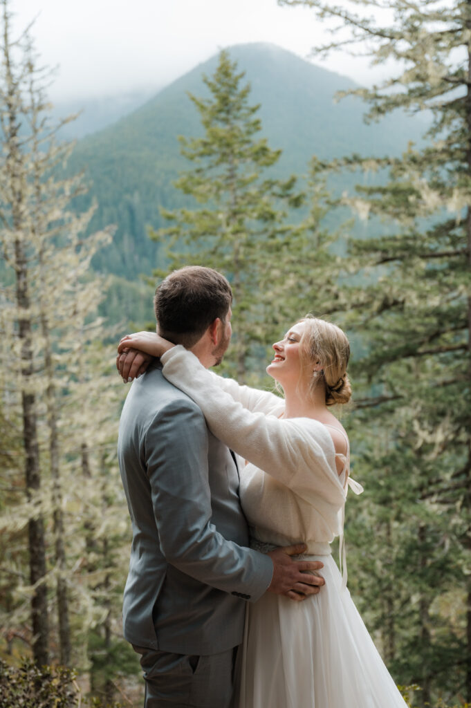 bride and groom sharing a moment with fog, mossy trees, and mountains in Olympic National Park