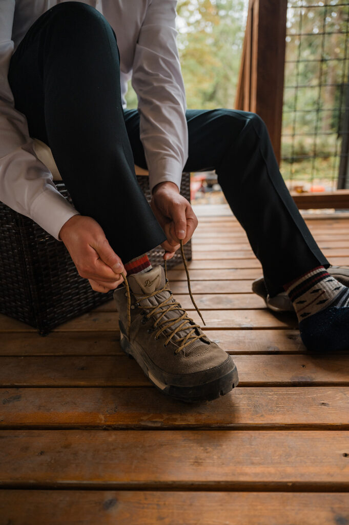 Groom laces up his boots for a hiking elopement on Skyline Trail