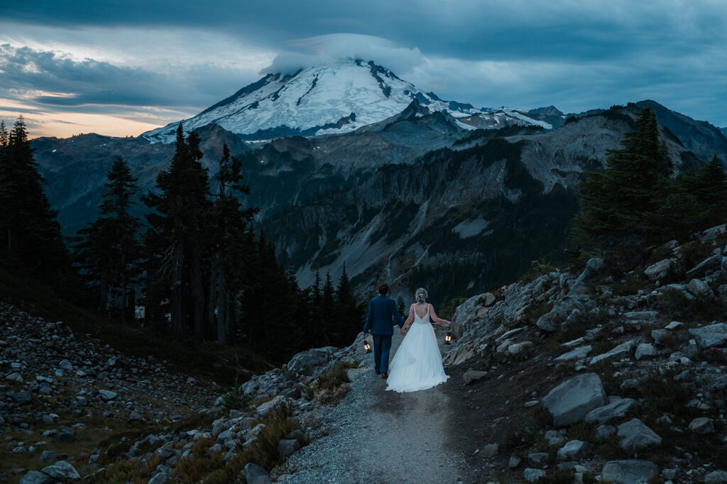 Bride and groom hike at dawn with lanterns at Artist Point