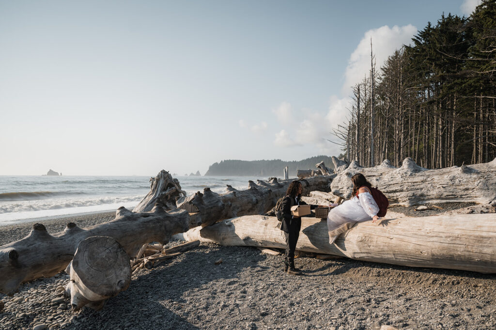 Couple climbs over large drift wood on Rialto Beach before they explore hole in the wall