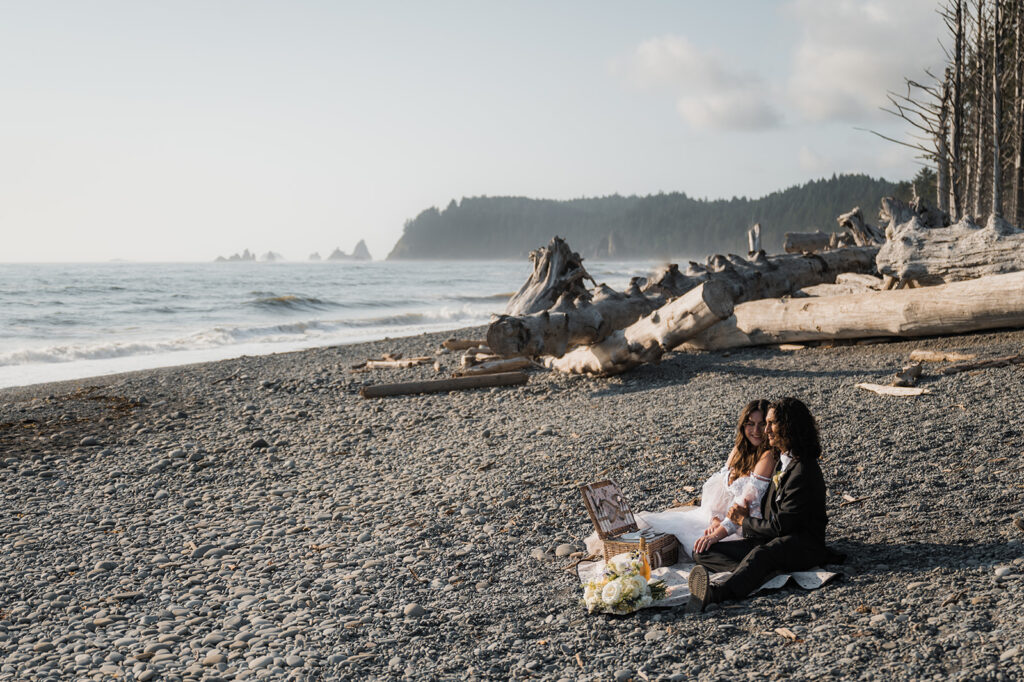 Elopement couple shares cake and snack on Rialto Beach before they explore hole in the wall