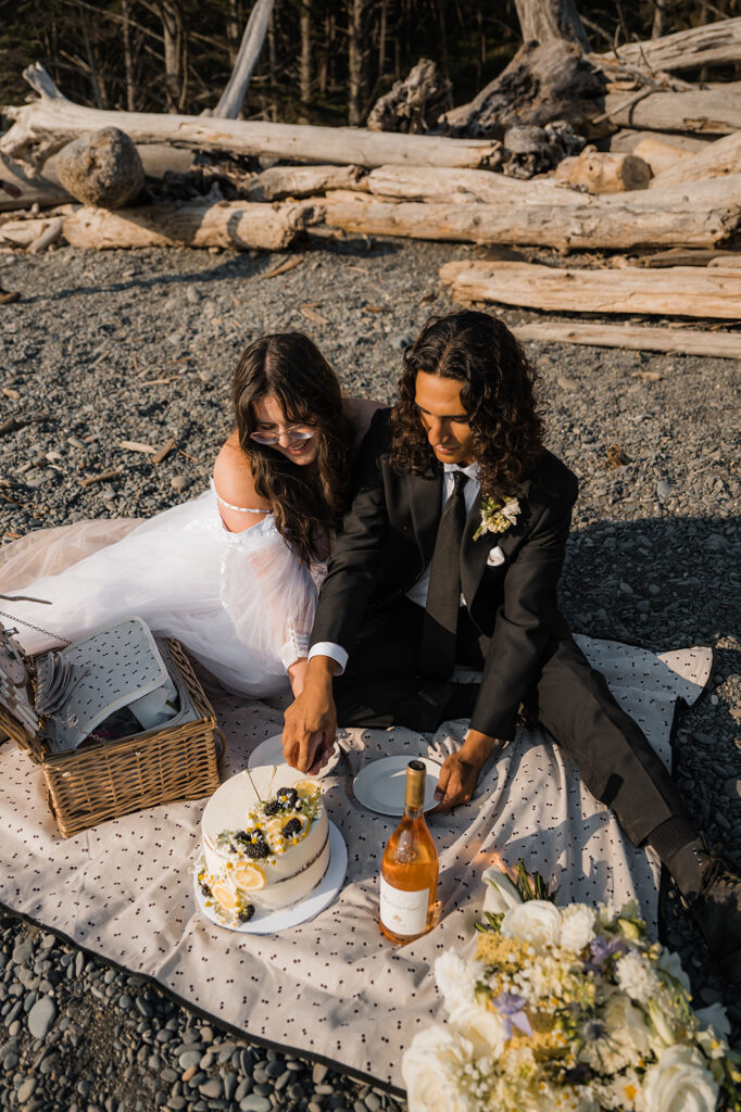 Elopement couple shares cake and snack on Rialto Beach before they explore hole in the wall