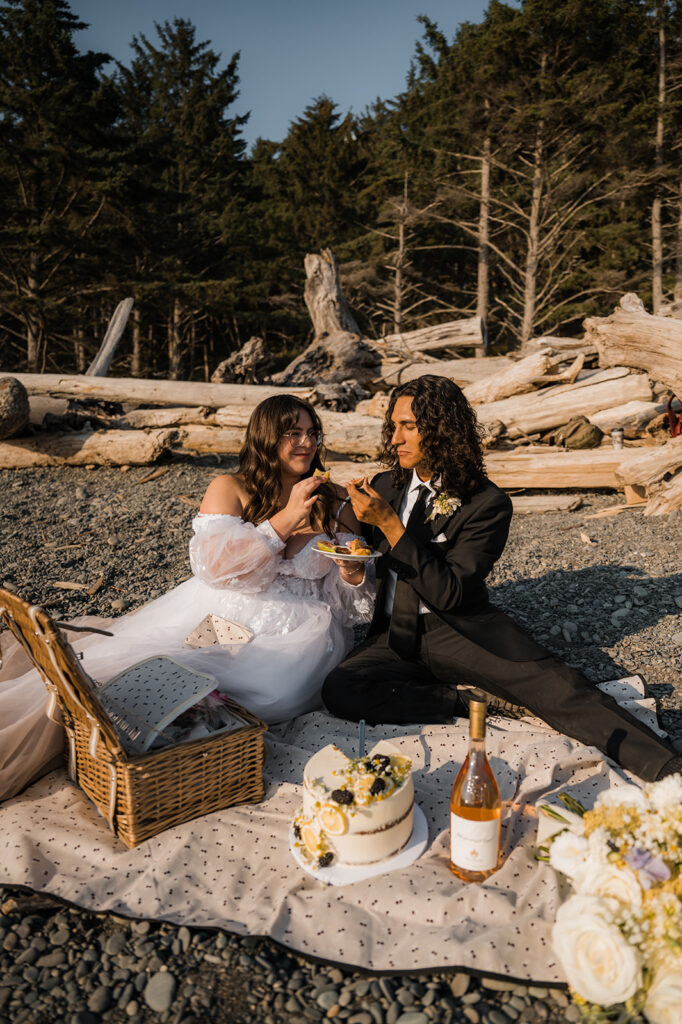 Elopement couple shares cake and snack on Rialto Beach before they explore hole in the wall