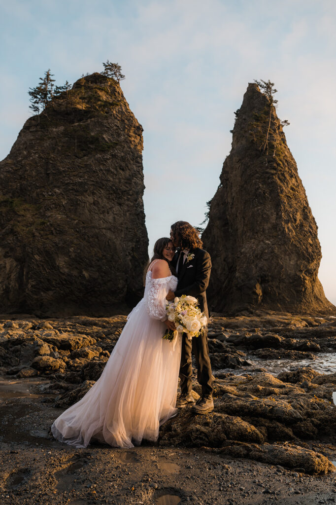 Bride and groom take a picture in the hole in the wall at rialto beach