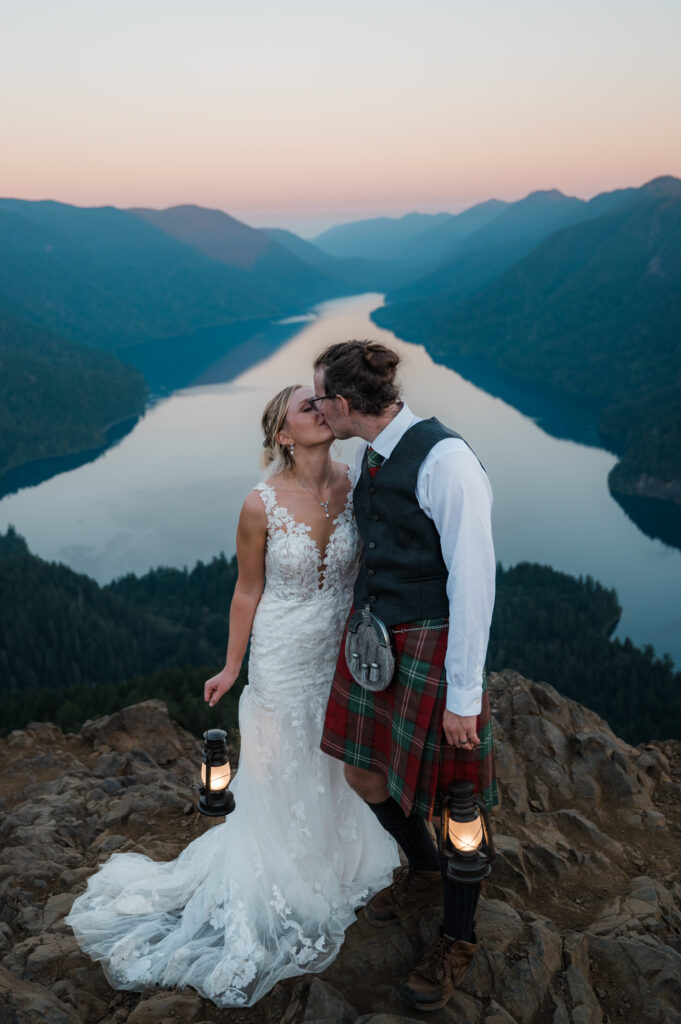 couple eloping on top of Mount Storm King in Olympic National Park while holding lanterns at sunrise 