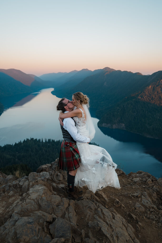 groom lifting up the bride on top of Mount Storm King with views of Lake Crescent and Olympic National Park in the background