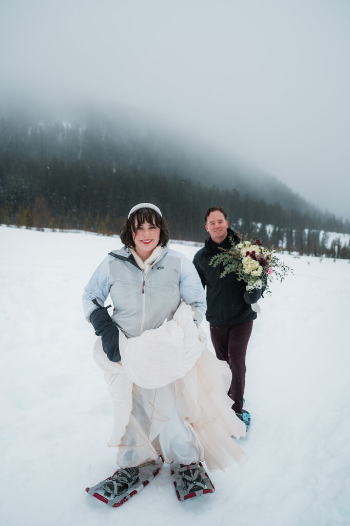 couple snowshoeing in their wedding attire during their winter elopement day in Oregon