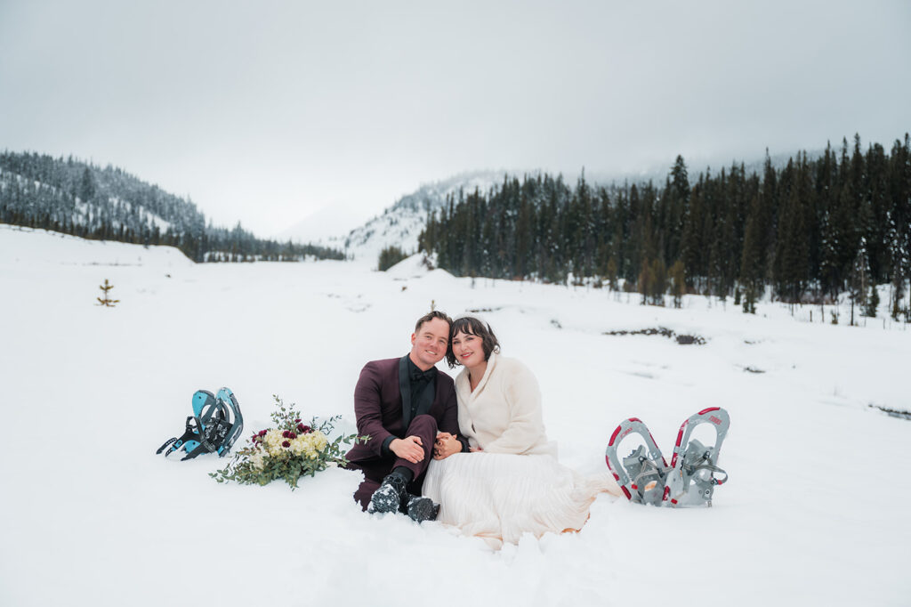 couple sitting in the snow in their wedding attire after snowshoeing at Mount Hood Oregon