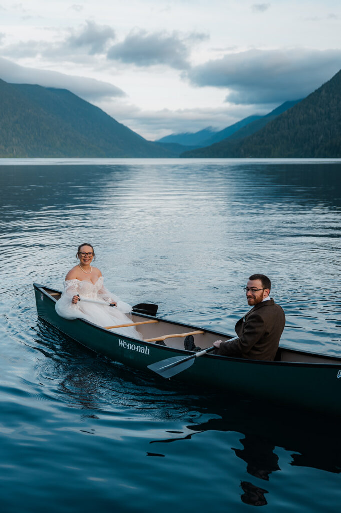 Couple laughing together in a canoe on a misty Lake Crescent morning, sunlight reflecting off the lake