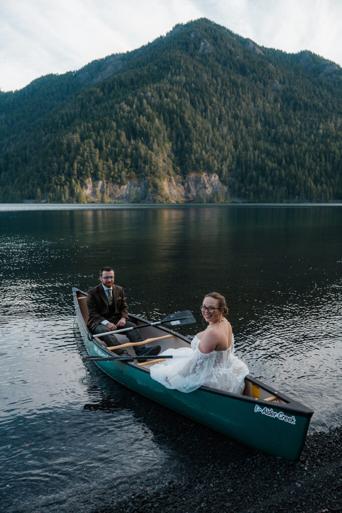 Couple laughing together in a canoe on a misty Lake Crescent morning, sunlight reflecting off the lake