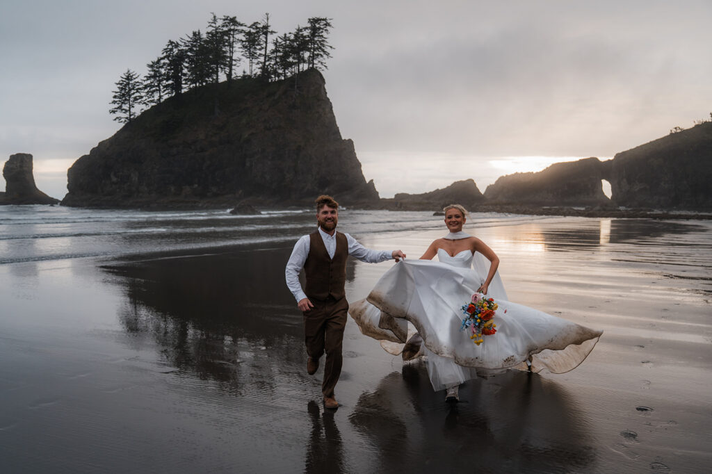 bride and groom running on the beach during their olympic national park elopement day in the pnw