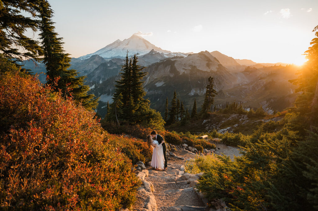 bride and groom kissing surrounded by fall colors, warm sunset light, and views of Mount Baker during their elopement at Artist Point