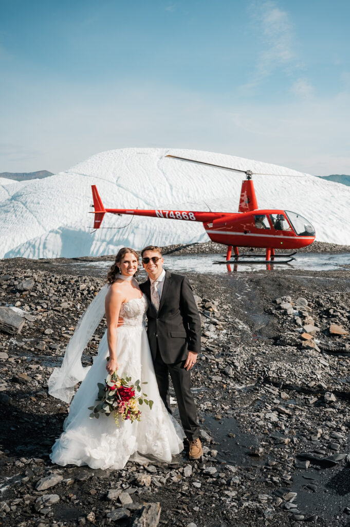 a couple standing in front of a helicopter during their alaska glacier elopement at matanuska glacier