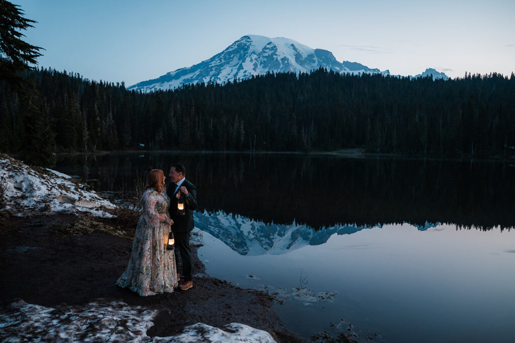 sunrise elopement at reflection lake with the couple holding lanterns and mt. rainier in the background